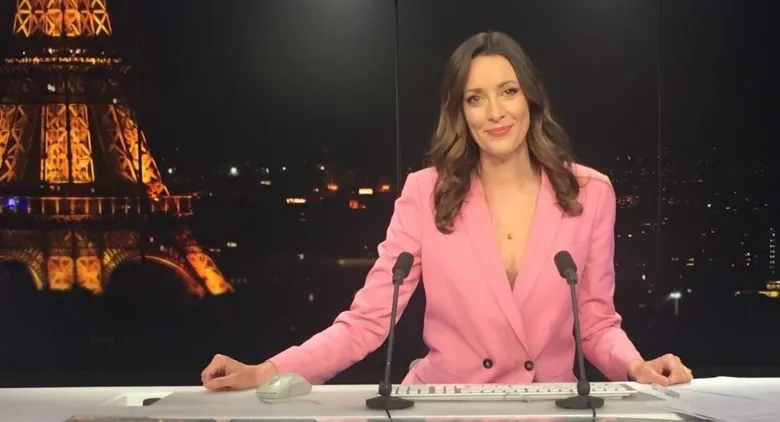 Charli James anchoring at the France 24 news desk, with the Eiffel Tower lit up behind her